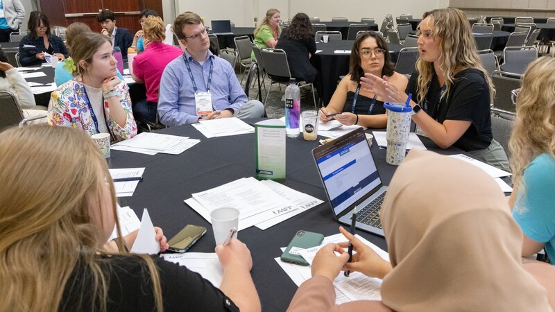 Attendees sitting around tables in discussion