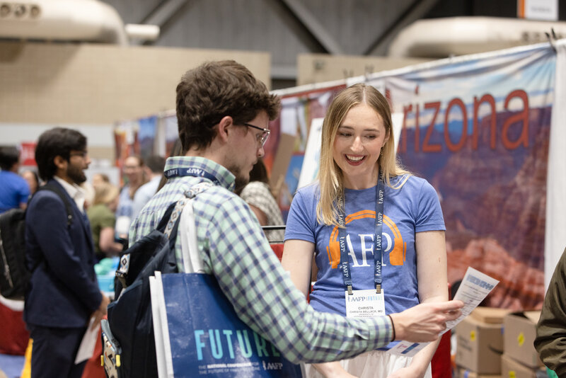 Woman exhibitor and male attendee talking at booth