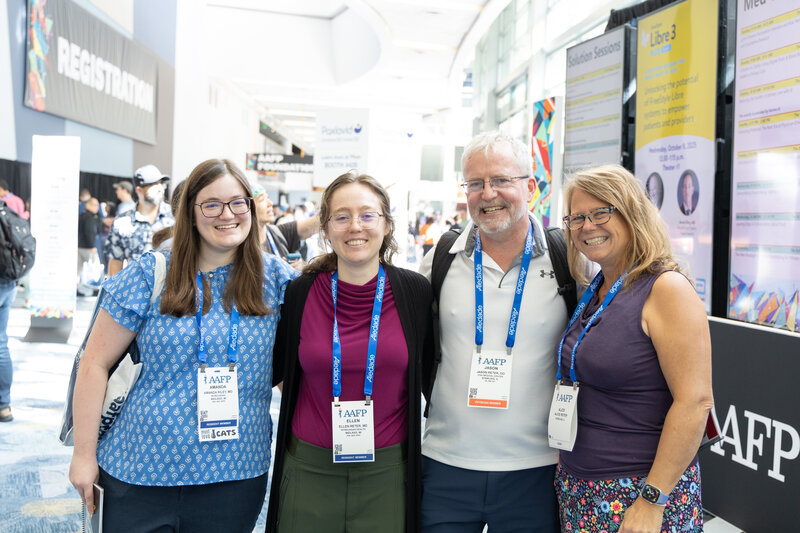 Four attendees smiling by registration in the convention center