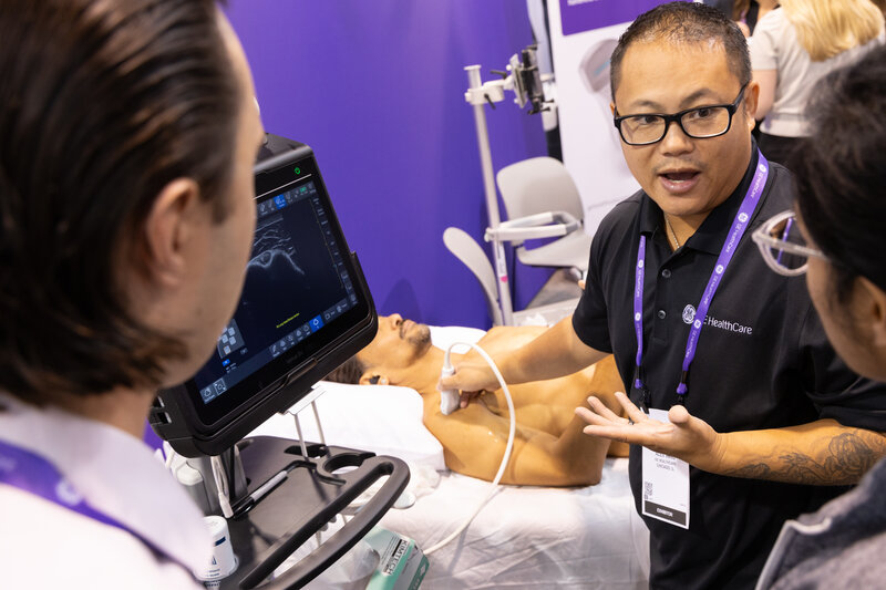 Male exhibitor demonstrating medical device to attendees