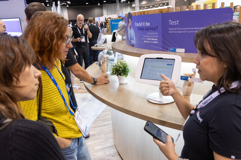 Two female attendees talking with a female exhibitor in the expo hall