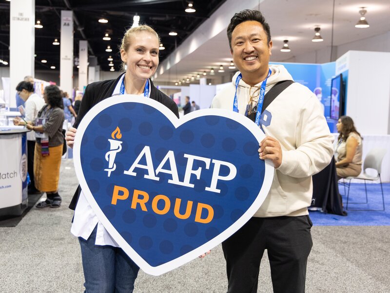 Young woman sitting at table smiling working on a laptop.