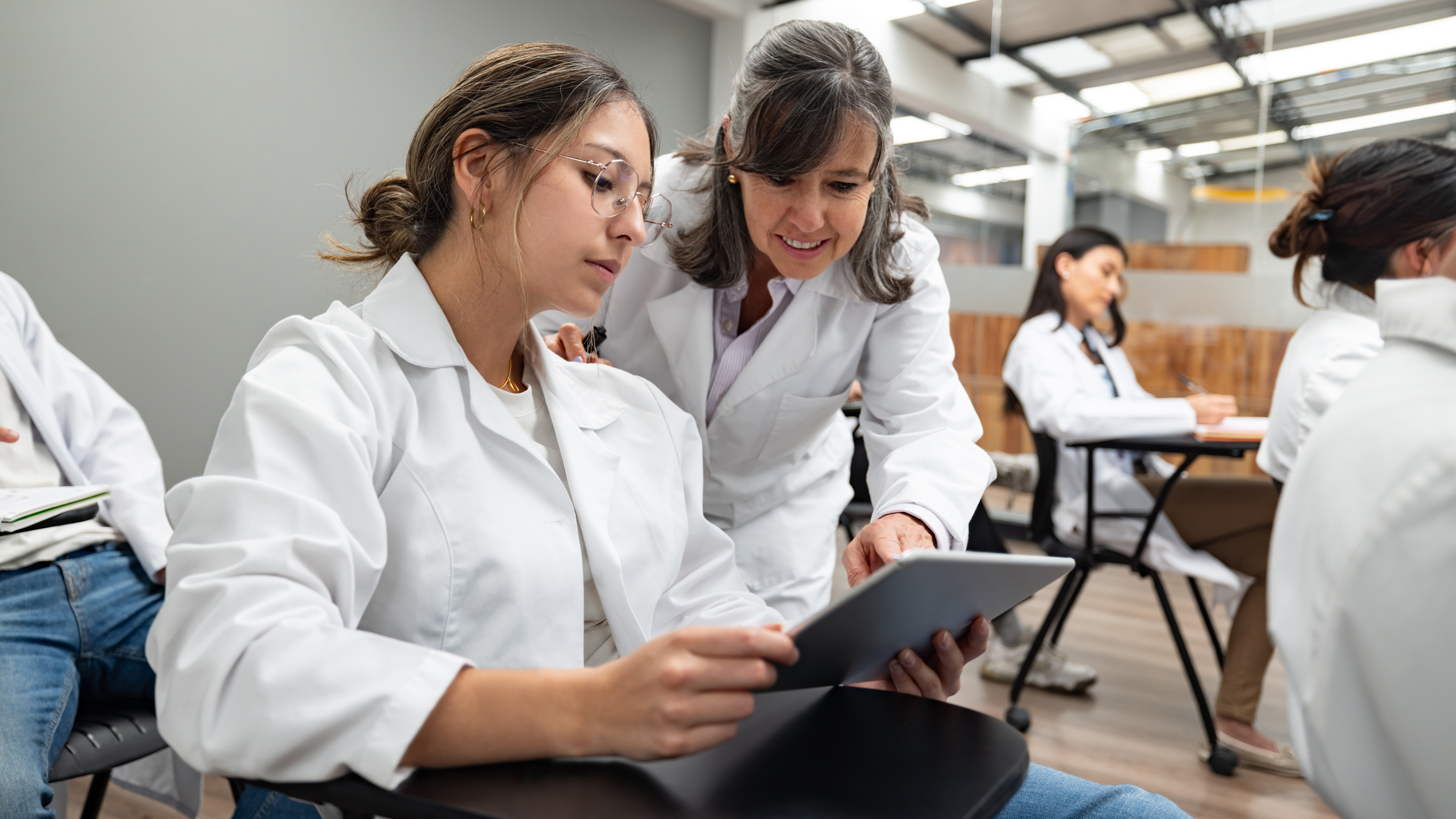 Image of residency program faculty looking at tablet with a student.
