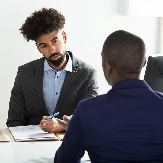 Young Businessman Interviewing Male Candidate In Office