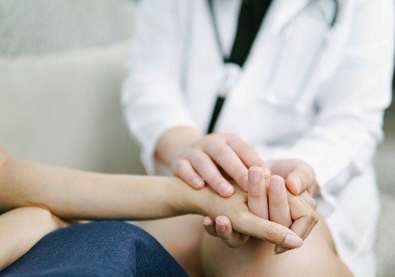 patient and healthcare provider holding hands in comfort