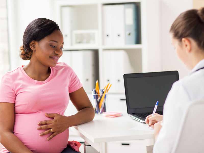 young pregnant woman speaking with physician
