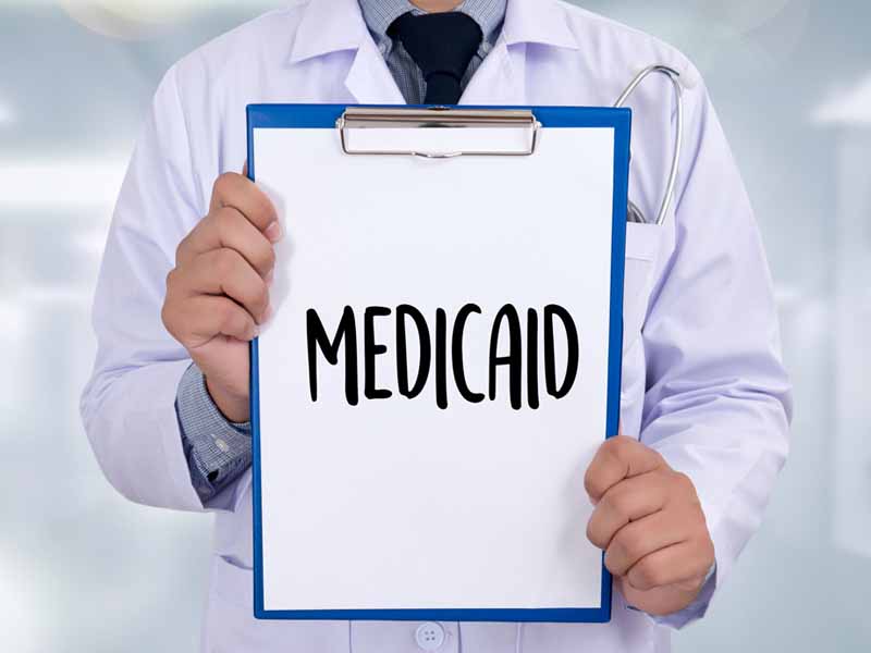 physician holding medicaid sign