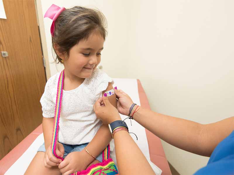 In this 2017 clinic photo, a health care professional bandages the injection site of a child who just received seasonal influenza vaccine.