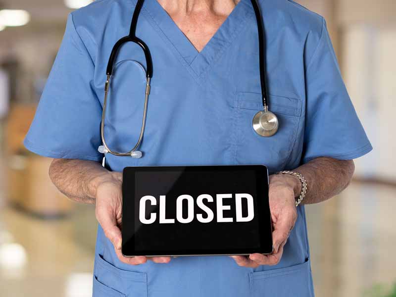 physician holding closed sign