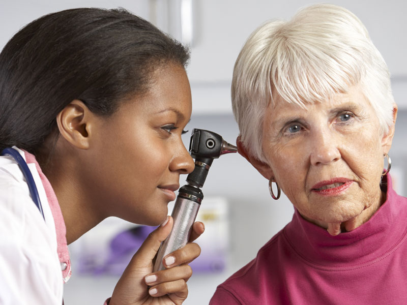 physician examining ear of elderly patient