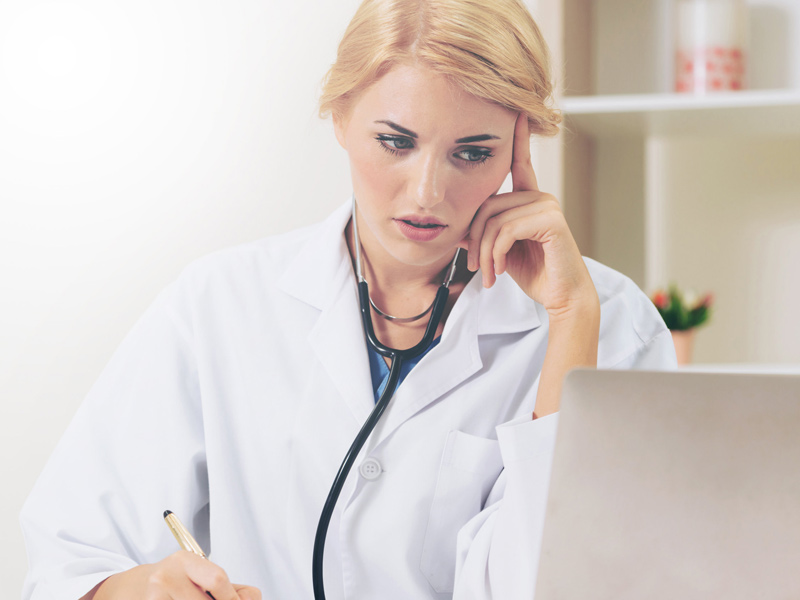 physician looking at computer and reviewing notes