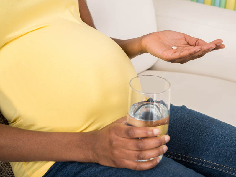pregnant woman with aspirin and glass of water