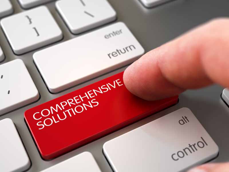 Index finger pressing red "comprehensive solutions" button on computer keyboard