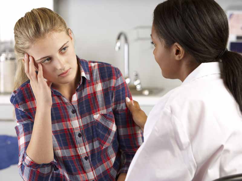 Doctor talking to sad teenage girl