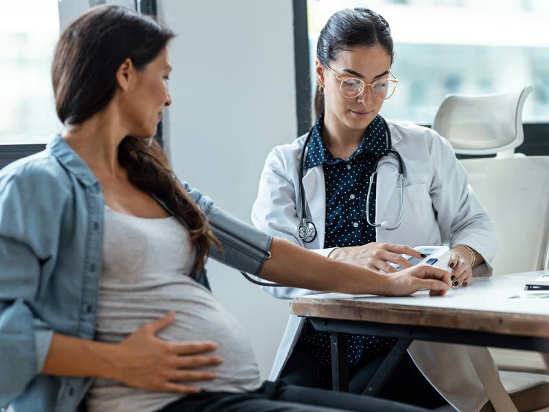 physician taking blood pressure of pregnant woman
