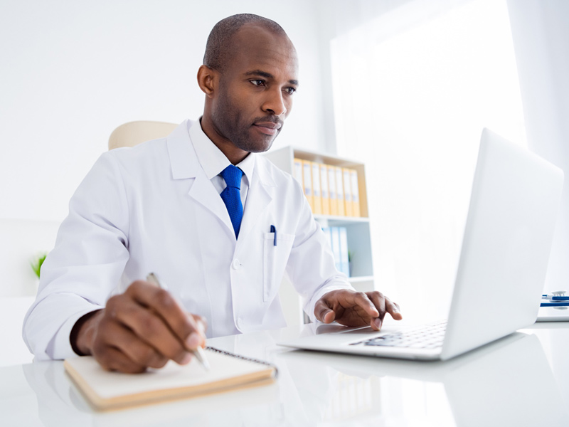 Black family doctor viewing data on laptop