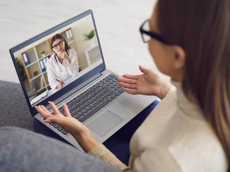 Doctor online. Female patient telling therapist using laptop webcam at home. The medical worker consults the girl remotely. Virtual hospital. Telemedicine.