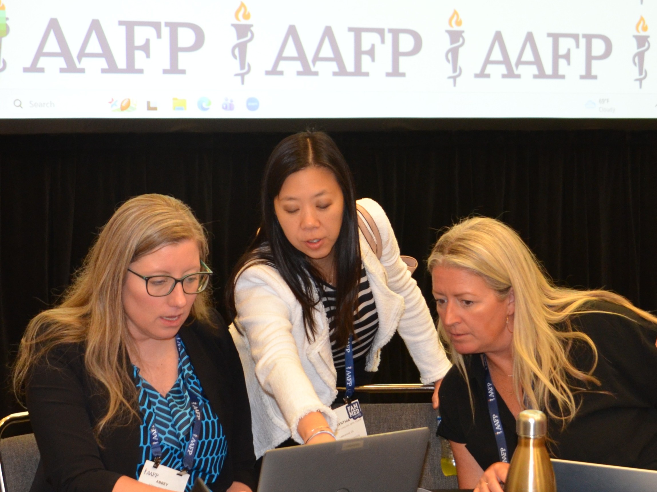 Three people under an AAFP banner looking at a laptop screen.